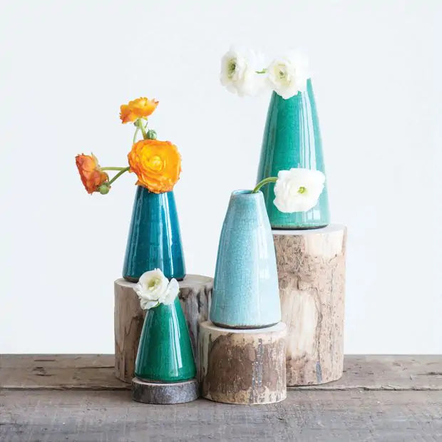 Set of teal ceramic vases with flowers on a wooden surface